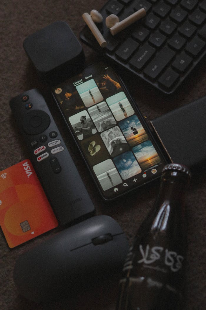 Close-up of gadgets on a desk including smartphone, remote, and keyboard.